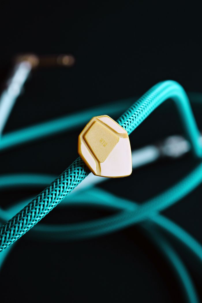 Services Detailed shot of a guitar pick on a turquoise audio cable, showcasing music equipment.