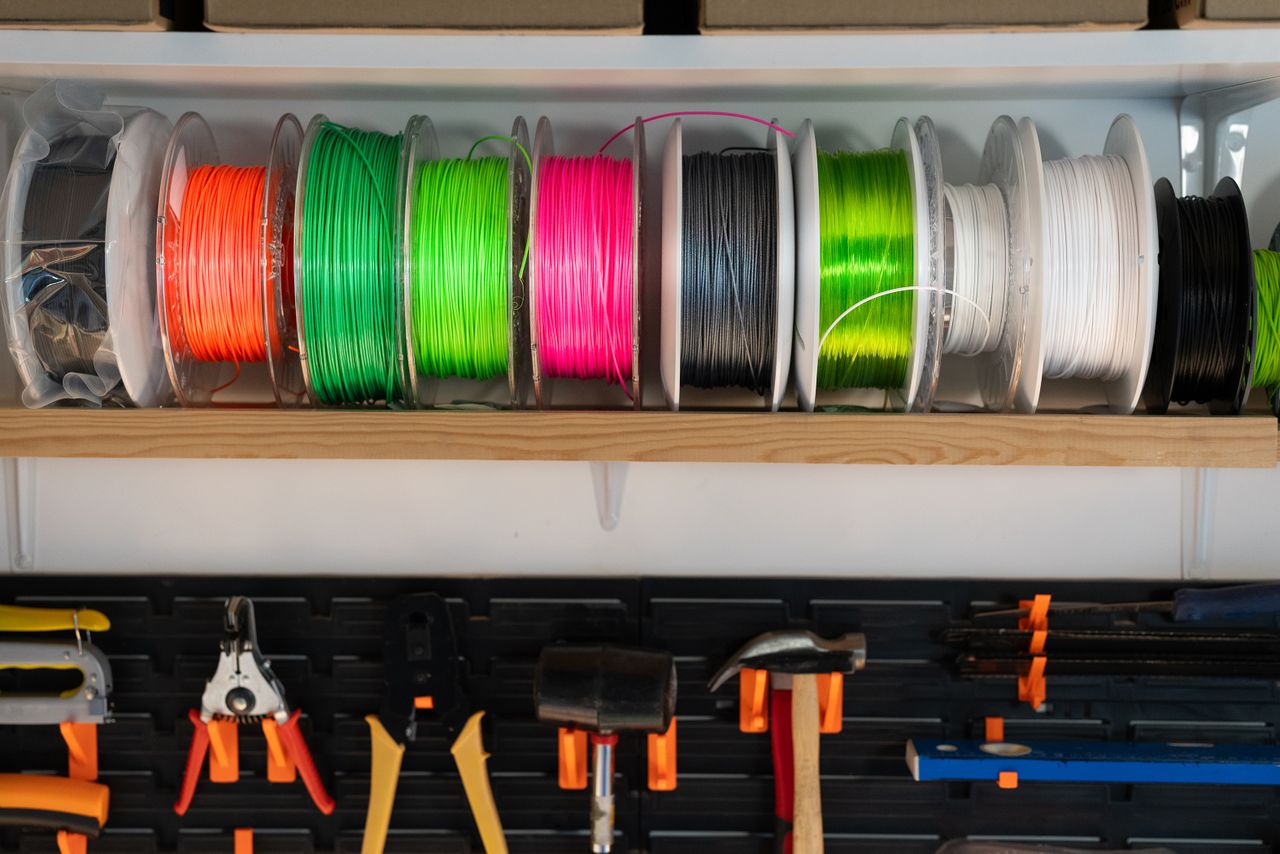 Mastering the First Impression: Your intriguing post title goes here A variety of colorful filament spools and tools organized on a workshop shelf, ideal for 3D printing enthusiasts.