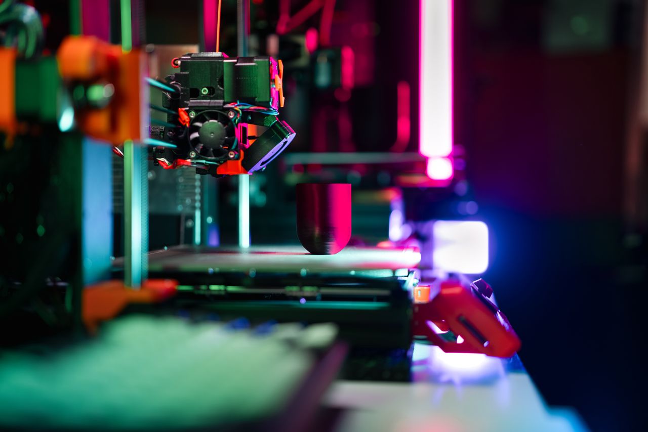 The Art of Drawing Readers In: Your attractive post title goes here Close-up of a modern 3D printer in a workshop, highlighted by neon lighting.